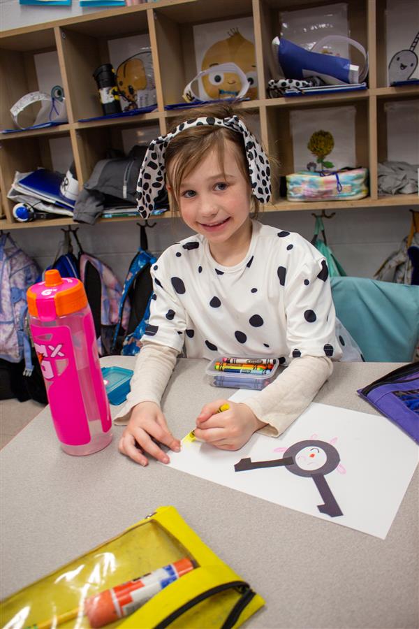 girl dressed as dalmatian dog writing on paper